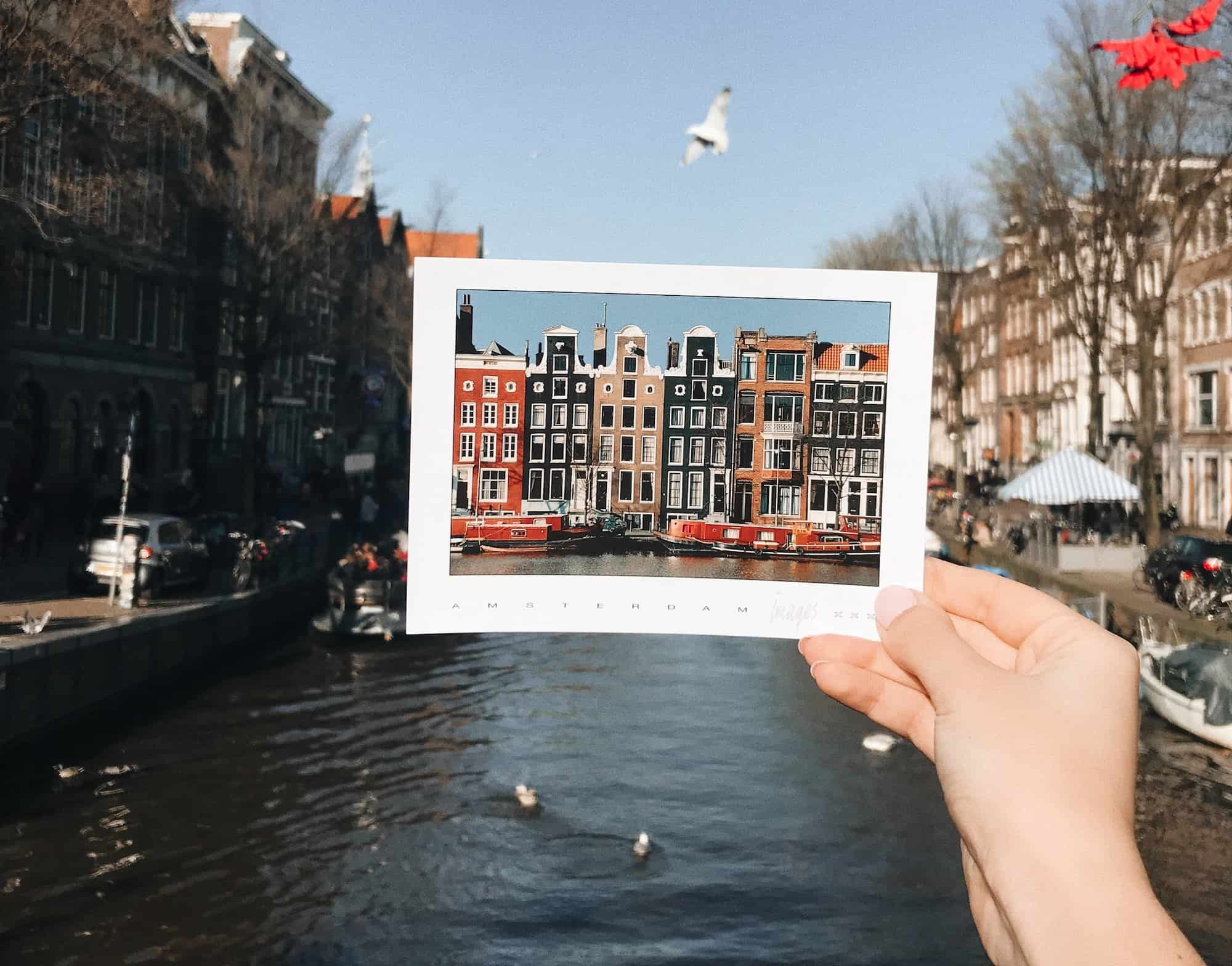 Person holds up a photograph of a riverside and buildings with the same river as a backdrop